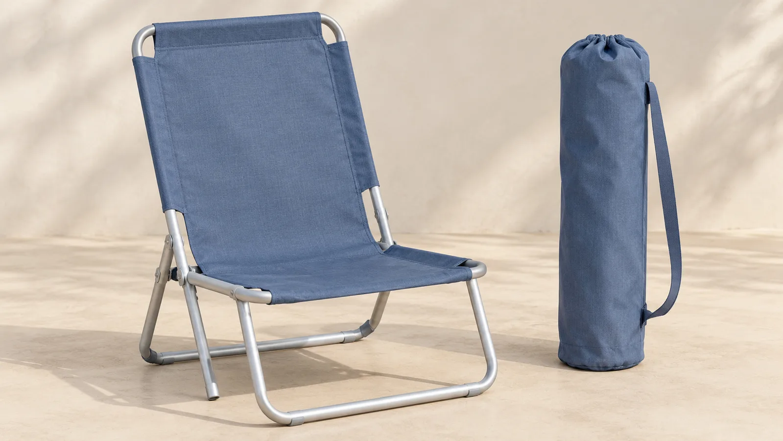 A plain folding beach chair shown open beside its matching packed carry bag